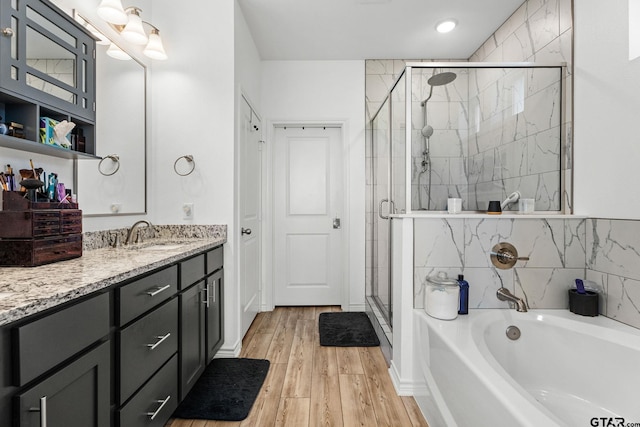 bathroom with hardwood / wood-style flooring, shower with separate bathtub, and vanity