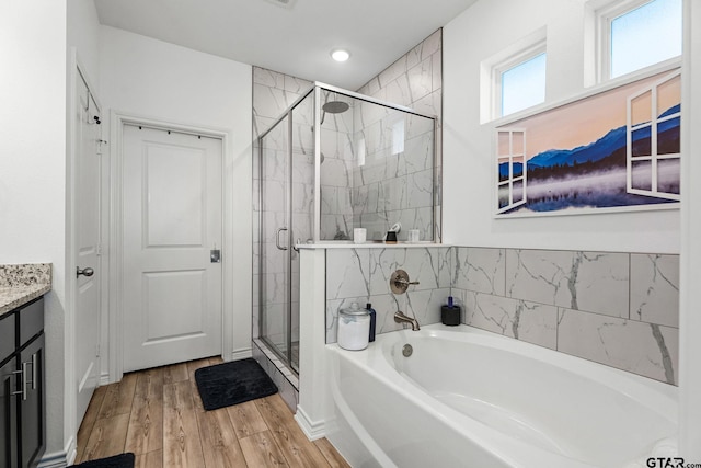 bathroom featuring hardwood / wood-style flooring, plus walk in shower, and vanity