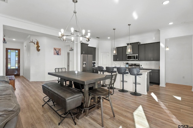 dining room with ornamental molding, a notable chandelier, and light hardwood / wood-style flooring