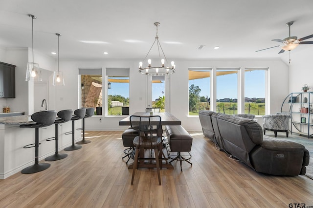 dining room featuring ornamental molding, light wood-type flooring, and ceiling fan with notable chandelier