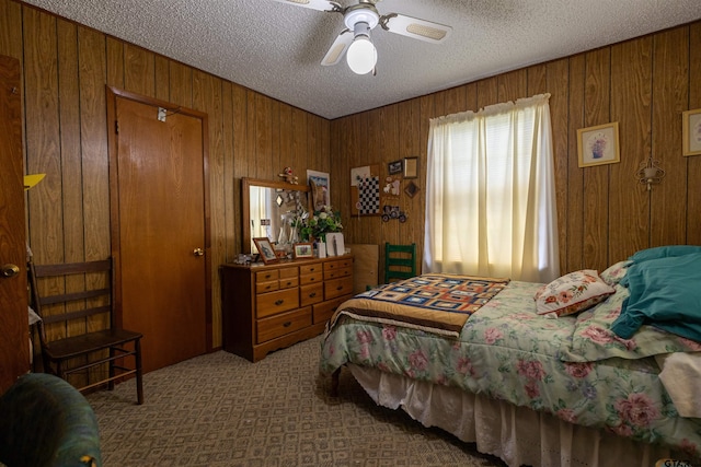 carpeted bedroom featuring wood walls, ceiling fan, and a textured ceiling