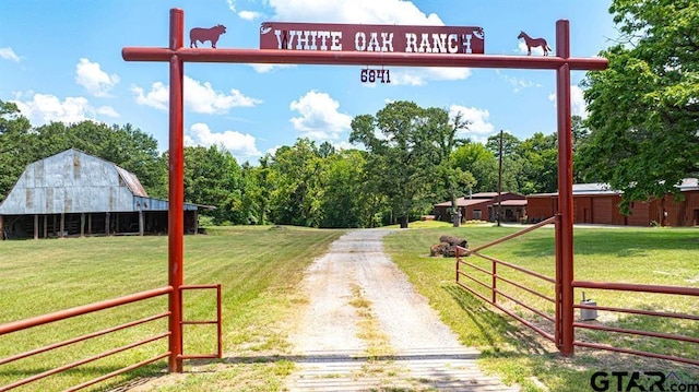 view of road with a rural view, driveway, a gated entry, and a barn