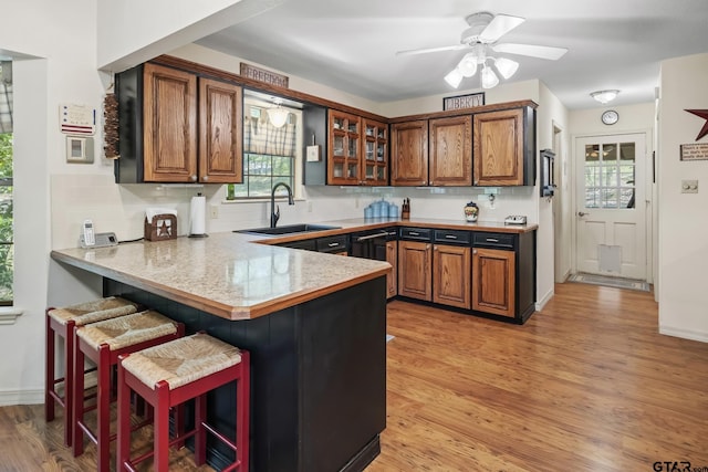 944 Clear Water Trl, Holly Lake Ranch, TX 75765 - kitchen with a sink, a peninsula, a breakfast bar, light wood finished floors, and brown cabinets