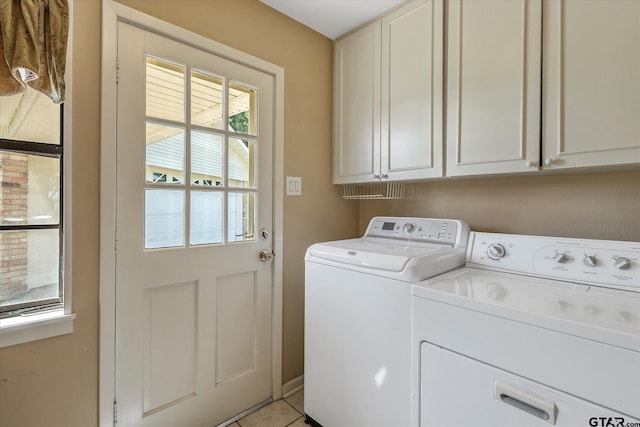 laundry area with washing machine and dryer, cabinets, and light tile patterned floors