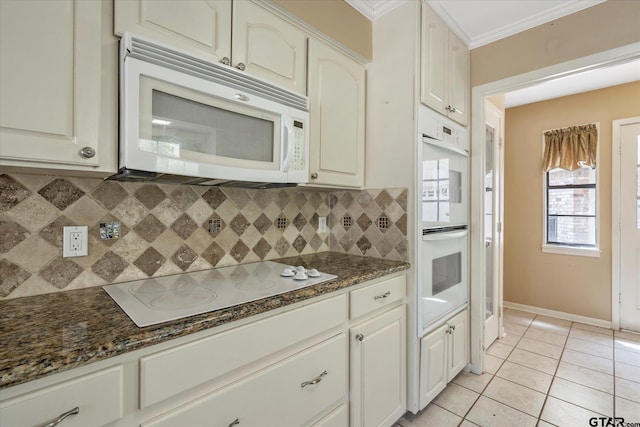 kitchen featuring dark stone counters, white cabinetry, backsplash, and white appliances