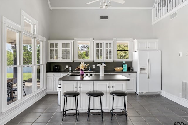 kitchen featuring white cabinetry, white fridge with ice dispenser, and a kitchen bar