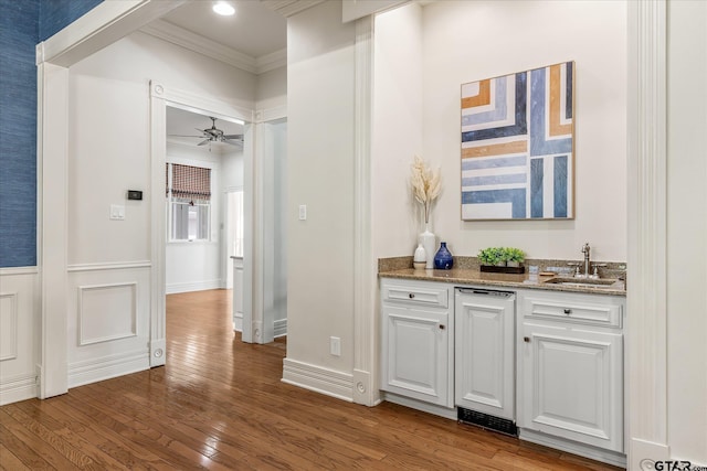 bar with hardwood / wood-style floors, sink, crown molding, white cabinetry, and stone countertops