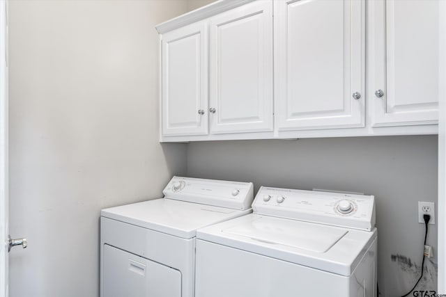 clothes washing area with separate washer and dryer and cabinets