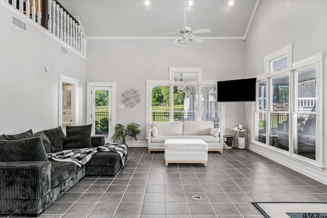 tiled living room with ceiling fan, a towering ceiling, and crown molding