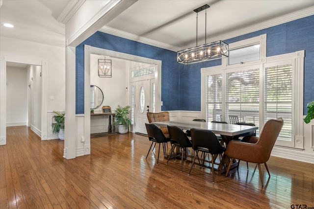 dining area with wood-type flooring, ornamental molding, and a chandelier