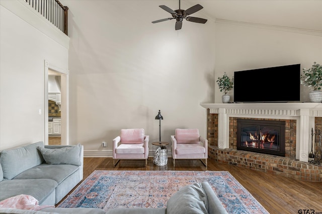 living room with a brick fireplace, dark hardwood / wood-style flooring, and ornamental molding