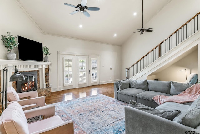 living room featuring a brick fireplace, crown molding, hardwood / wood-style flooring, and ceiling fan