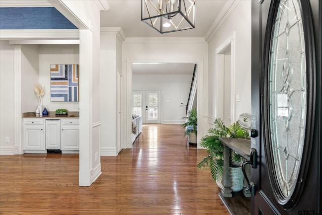 entrance foyer with french doors, dark wood-type flooring, crown molding, and a notable chandelier