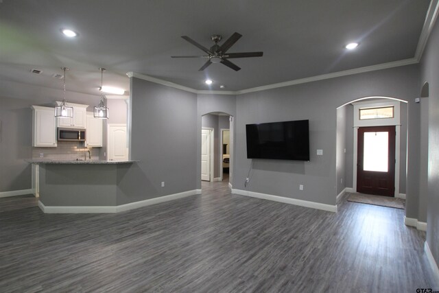 1700 Easy St, Tyler, TX 75703 - unfurnished living room featuring arched walkways, dark wood-style floors, a ceiling fan, recessed lighting, and crown molding