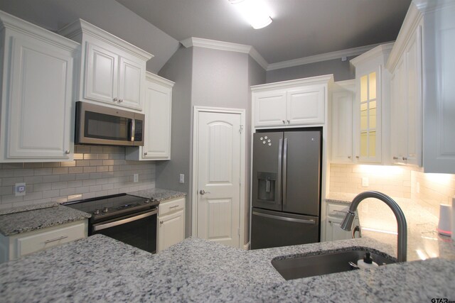 1700 Easy St, Tyler, TX 75703 - kitchen with appliances with stainless steel finishes, white cabinetry, light stone counters, decorative backsplash, and ornamental molding