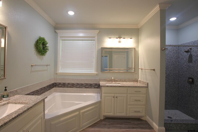 1700 Easy St, Tyler, TX 75703 - bathroom featuring a bath, wood finished floors, two vanities, a tile shower, and ornamental molding
