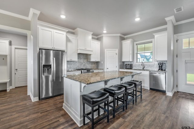 7757 Freestone Dr, Bullard, TX 75757 - kitchen with stainless steel appliances, dark stone countertops, a kitchen island, white cabinetry, and a kitchen breakfast bar