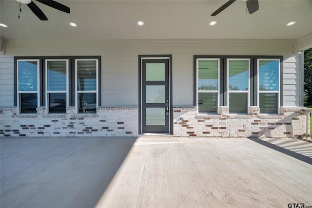 property entrance with a ceiling fan and brick siding