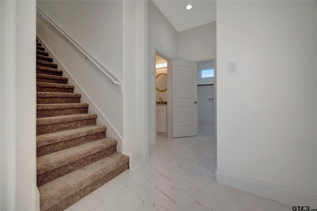 stairway with recessed lighting, marble finish floor, and baseboards