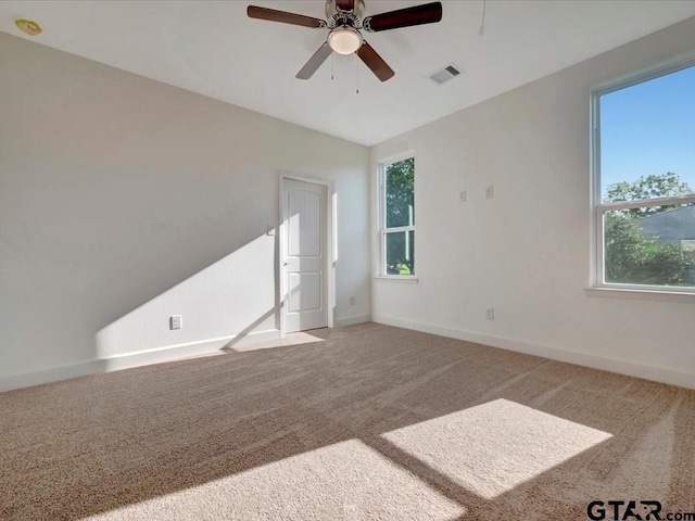 carpeted spare room with baseboards, visible vents, and ceiling fan