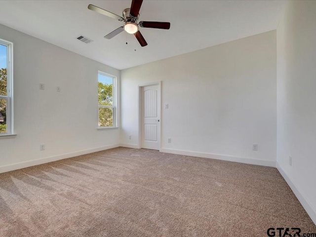 unfurnished room with baseboards, ceiling fan, visible vents, and light colored carpet