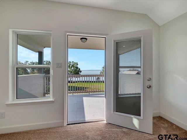 doorway to outside with lofted ceiling, baseboards, and carpet