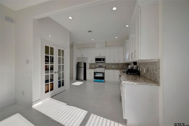 kitchen with french doors, stainless steel appliances, decorative backsplash, white cabinetry, and a sink