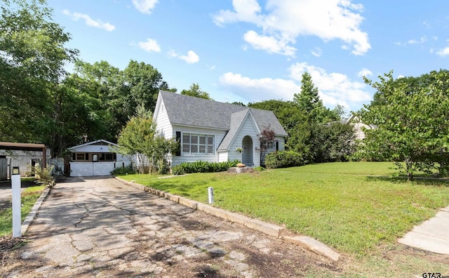 tudor-style house featuring a front lawn, a shingled roof, and aphalt driveway