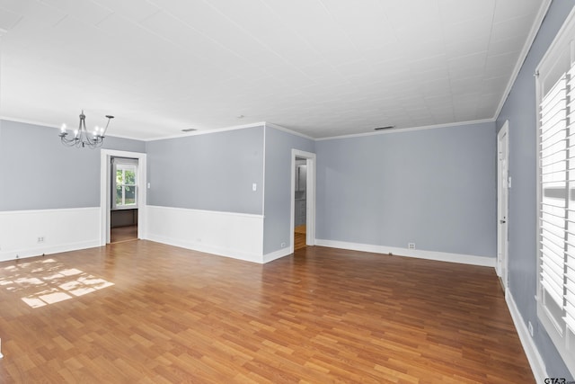 unfurnished living room with baseboards, a notable chandelier, light wood-style flooring, and crown molding