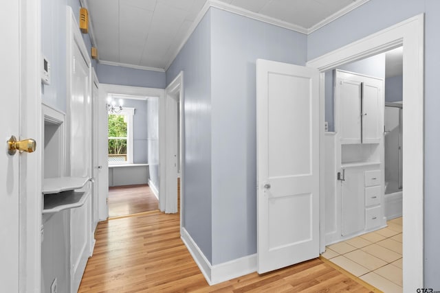hallway with crown molding, light wood-style flooring, and a notable chandelier