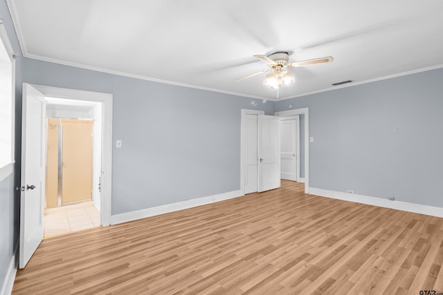 spare room with light wood-style flooring, a ceiling fan, crown molding, visible vents, and baseboards