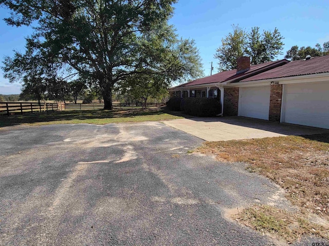 view of home's exterior with a garage and a rural view