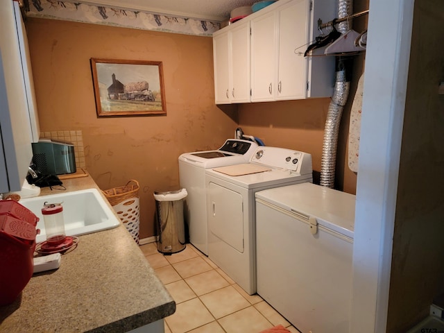 laundry room with cabinets, separate washer and dryer, light tile patterned floors, and sink