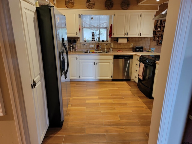 kitchen with stainless steel appliances, white cabinetry, sink, and backsplash