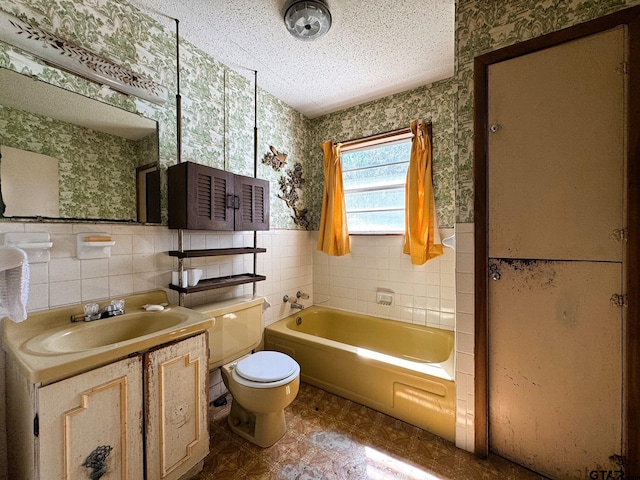 bathroom with vanity, a textured ceiling, toilet, and tile walls