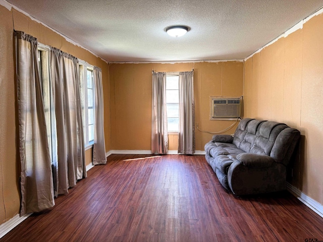 sitting room featuring a healthy amount of sunlight, an AC wall unit, a textured ceiling, and dark hardwood / wood-style floors