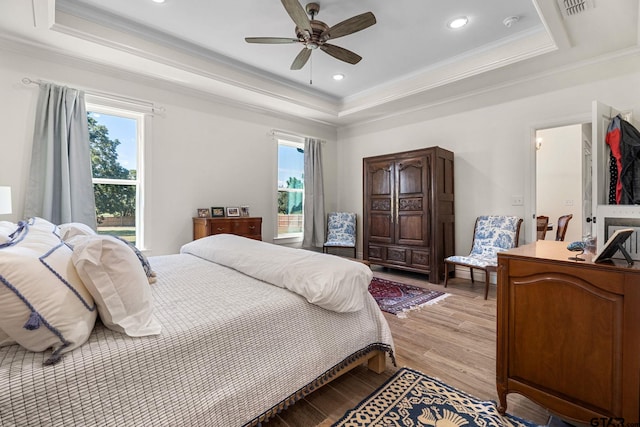 bedroom featuring ceiling fan, light wood-type flooring, crown molding, and a tray ceiling