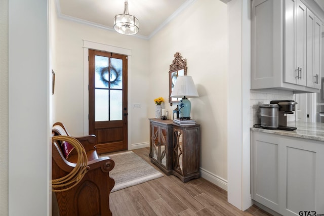 entrance foyer featuring light hardwood / wood-style floors, an inviting chandelier, and ornamental molding