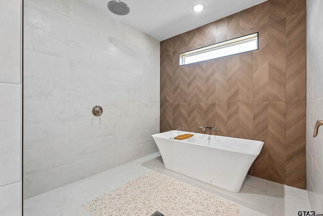 bathroom with tile walls, tile patterned flooring, and plus walk in shower