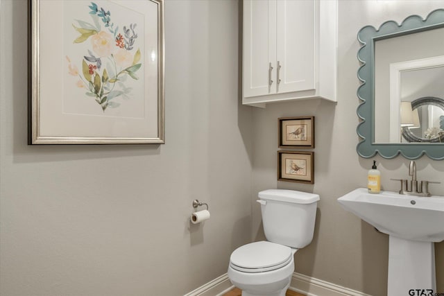 bathroom featuring toilet, baseboards, and a sink