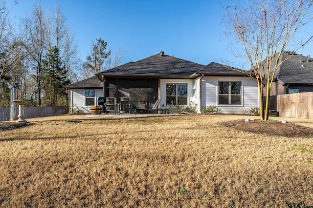 back of property with a sunroom, a yard, and fence