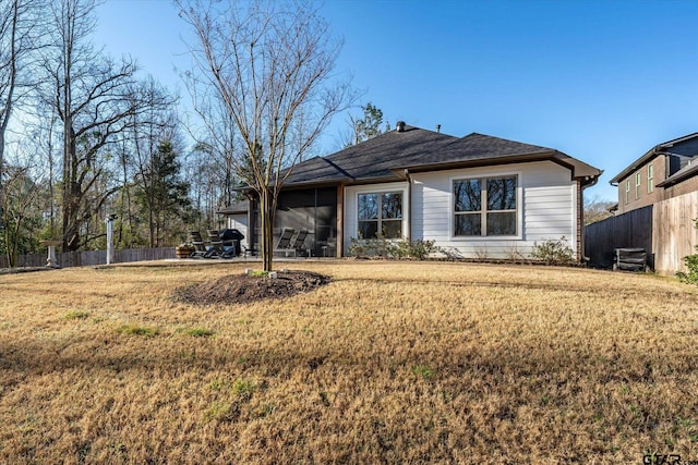 back of property featuring a yard, a sunroom, and fence