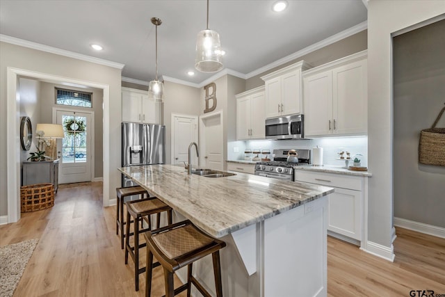 kitchen with crown molding, a breakfast bar area, appliances with stainless steel finishes, white cabinetry, and a sink