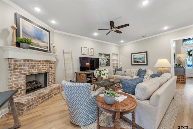 living room with wood finished floors, visible vents, recessed lighting, ornamental molding, and a brick fireplace