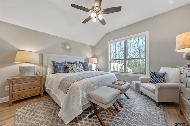 bedroom featuring baseboards, lofted ceiling, light wood-style floors, and a ceiling fan