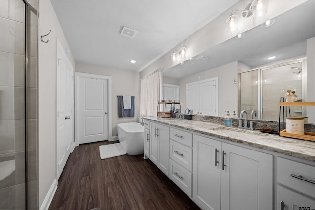 409 Meadow Ln, Chandler, TX 75758 - bathroom featuring double vanity, a stall shower, wood finished floors, a freestanding bath, and recessed lighting