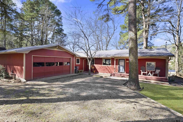 view of front of property featuring a garage, driveway, a front lawn, and metal roof