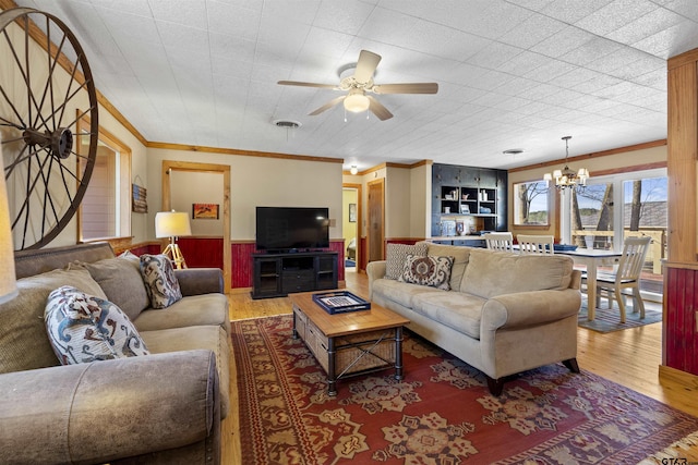 living area with a wainscoted wall, visible vents, crown molding, and wood finished floors