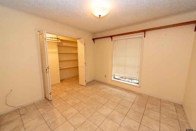 unfurnished bedroom featuring a closet, light tile patterned flooring, and a textured ceiling