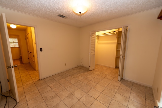 unfurnished bedroom with light tile patterned floors, a textured ceiling, and a closet